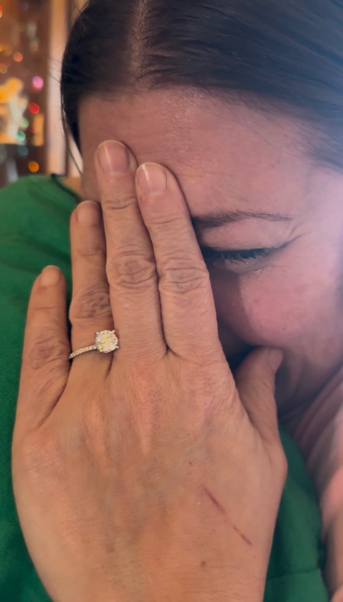 Heather wiping away tears, her engagement ring on her finger