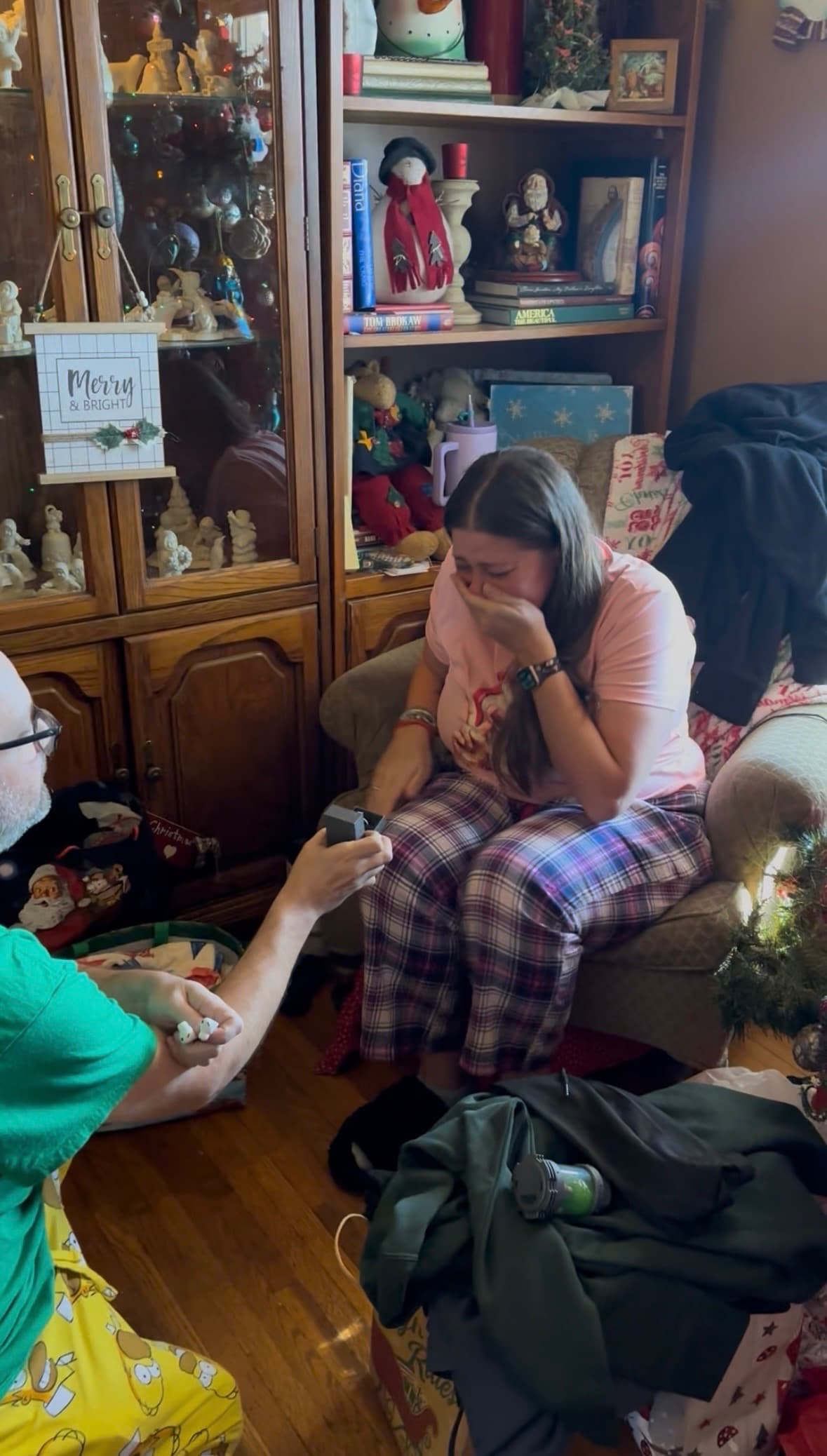 Benjamin on one knee holding out a ring box as Heather covers her face in tears